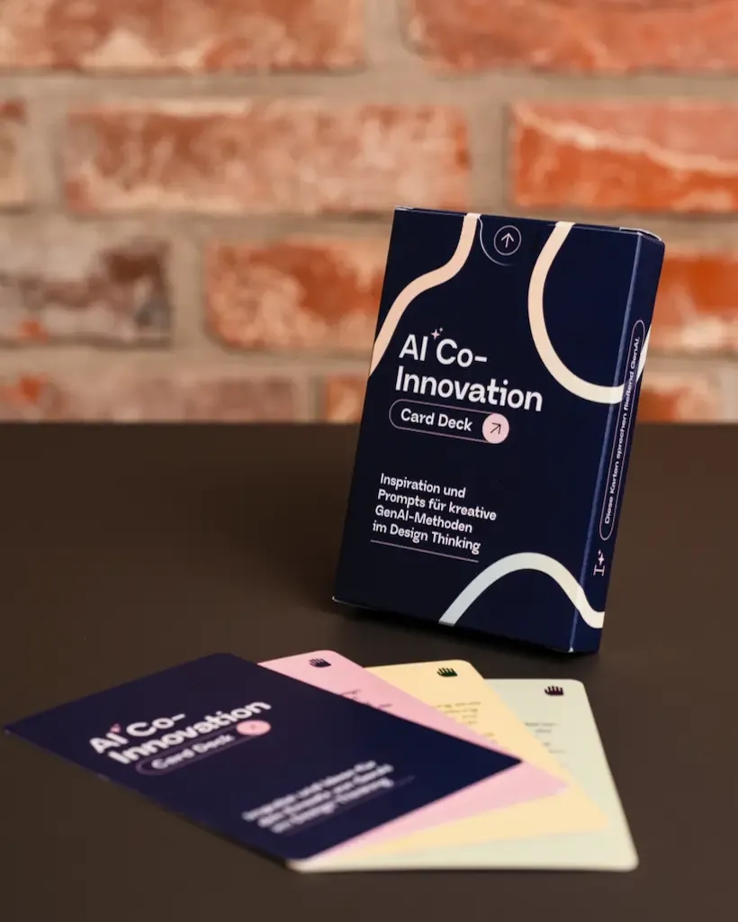 AI Co-Innovation Card Deck auf einem Tisch mit mehreren bunten Methodenkarten davor, verwendet für generative KI-gesteuerte Design Thinking-Workshops.